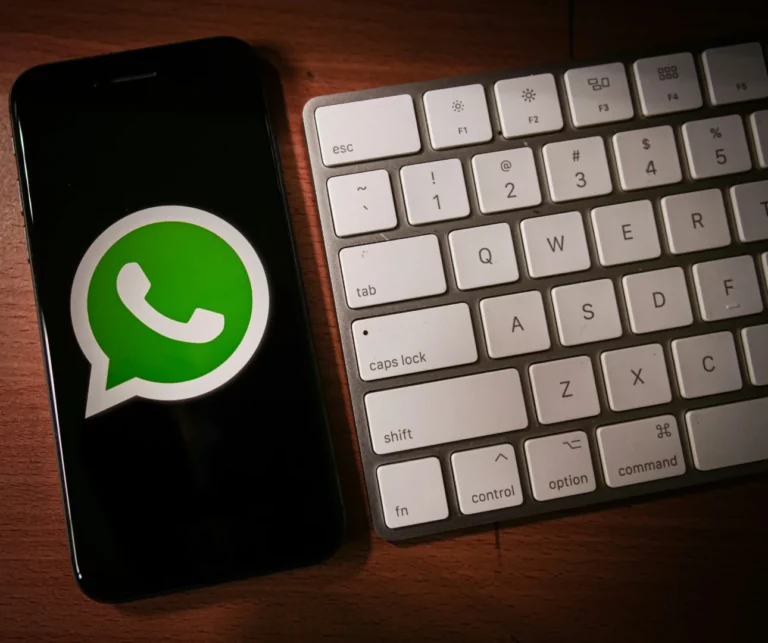 Smartphone affichant le logo WhatsApp à côté d'un clavier Mac - raccourcis de formatage texte